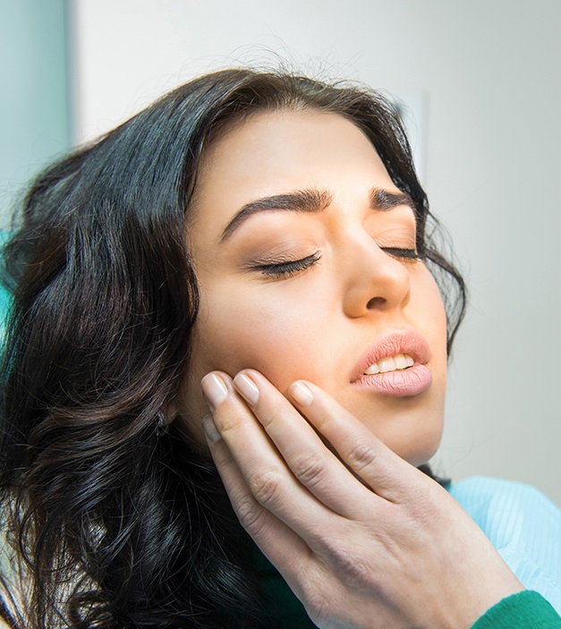 Woman holding jaw before wisdom tooth extraction