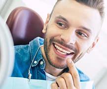 Man smiling at reflection in handheld mirror