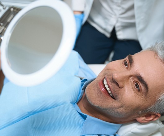 A man looking in the mirror at his smile