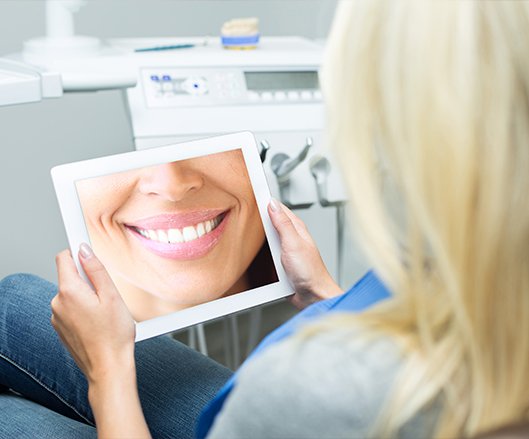 Woman looking at virtual smile design on tablet computer