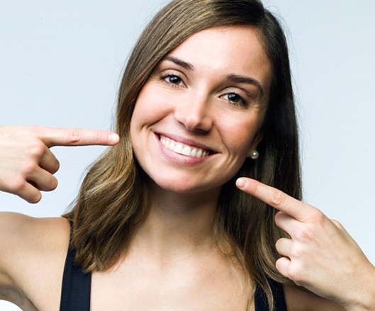 Woman pointing to her smile after dental bonding.