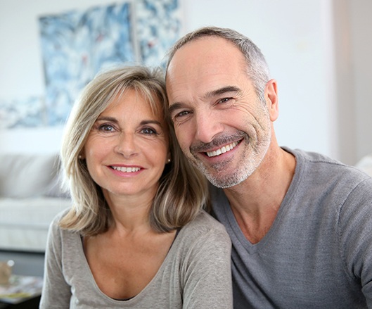 Older man and woman smiling after dental implant tooth replacement