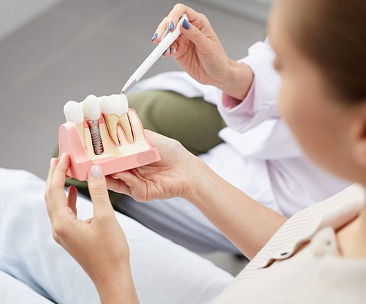 Dentist and patient looking at dental implant model