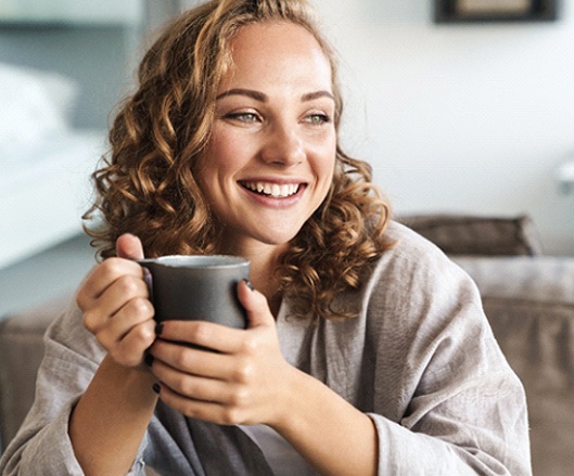 a person smiling and holding a coffee mug