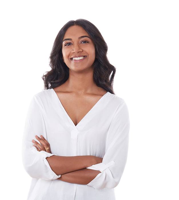 A young woman wearing a white blouse with her arms crossed and smiling after getting rid of her gummy smile in Ellicott City