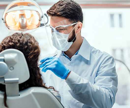 A male dentist examines a female patient’s smile to determine if she’s a candidate for gum recontouring