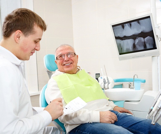A dentist going over how dental implant placement will work for an older male patient