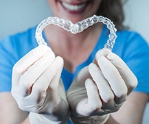 dentist holding two Invisalign aligners in the shape of a heart 