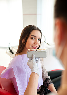 Dentist comparing patient's smile to tooth shade chart