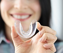 young woman holding up mouthguard