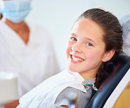 Child in dental chair smiling after fluoride treatment