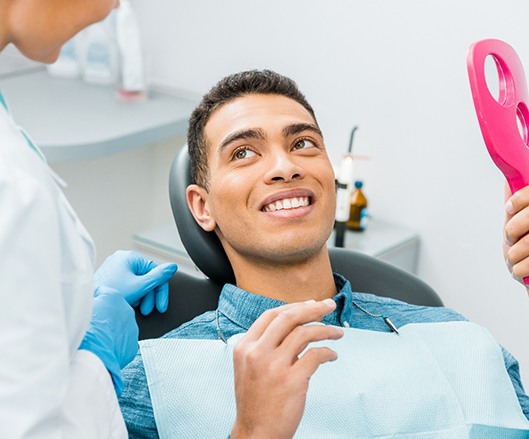 Dental patient holding mirror during visit with prosthodontist