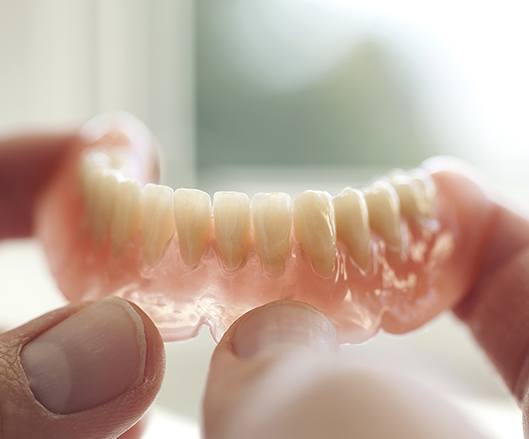 Hand holding a full denture