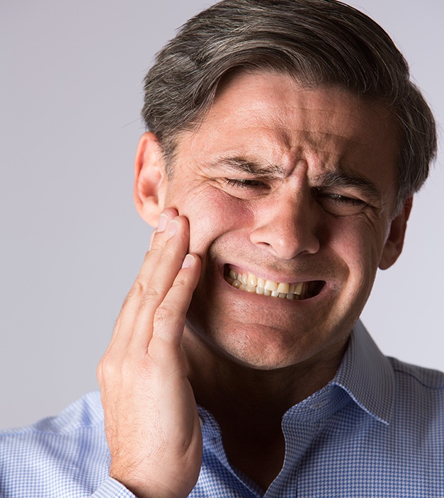Man in need of T M J therapy holding jaw