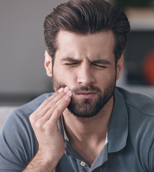 Man in need of tooth extraction holding jaw