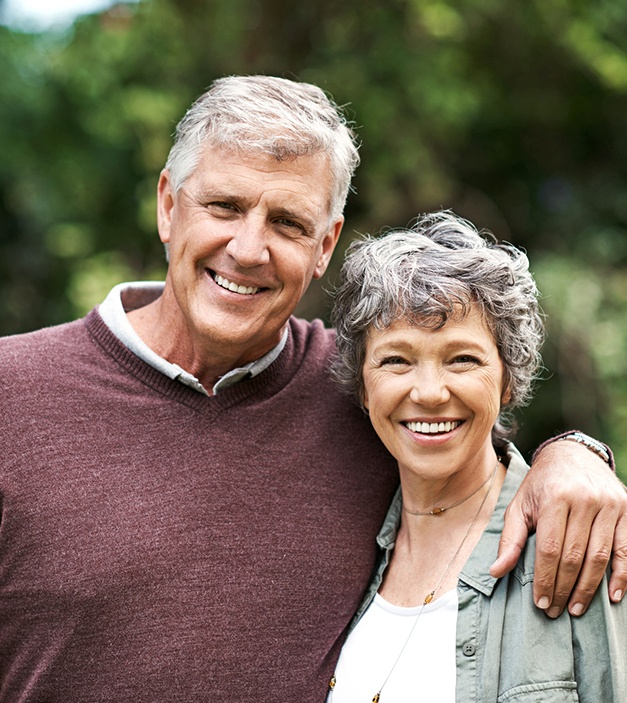 Older man and woman sharing smiles after dental crown and bridge placement