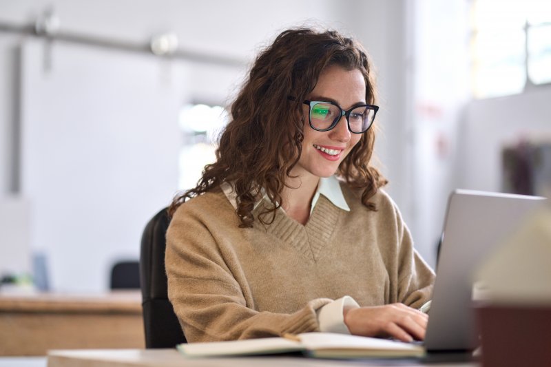 Patient smiling at computer searching for a dentist near you